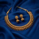 Antique gold-tone beaded drop necklace with textured scroll detailing and matching jhumka earring