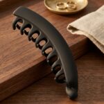 Large matte hair claw clip in black on wooden surface – SunShoppers UK