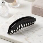 Glossy black acetate hair claw clip on marble surface – SunShoppers UK