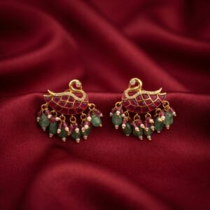 Gold-tone swan stud earrings with ruby-coloured jadau-style panel, green and pink bead drops and faux pearls on red fabric