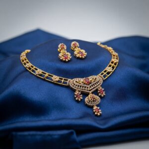 Gold-tone heart pendant necklace set with cubic zirconia, ruby-coloured stones and matching drop earrings on royal blue fabric