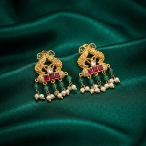 Antique gold-tone elephant earrings with ruby-coloured stones, green bead drops and faux pearl drops on green fabric