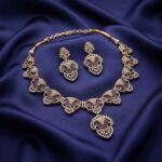 Gold-tone purple necklace set with openwork medallions, cubic zirconia, adjustable chain and matching drop earrings on navy fabric