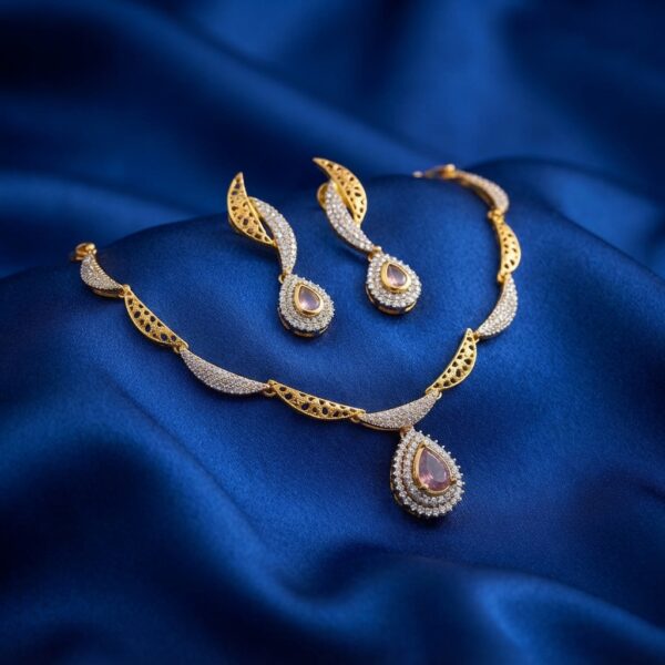 Gold-tone teardrop necklace set with cubic zirconia, blush-pink centre stones and matching drop earrings on royal blue fabric