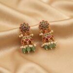 Antique gold-tone mini jhumka earrings with floral stud tops, ruby-coloured and green stones, green bead drops and faux pearls on champagne fabric