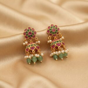 Antique gold-tone mini jhumka earrings with floral stud tops, ruby-coloured and green stones, green bead drops and faux pearls on champagne fabric