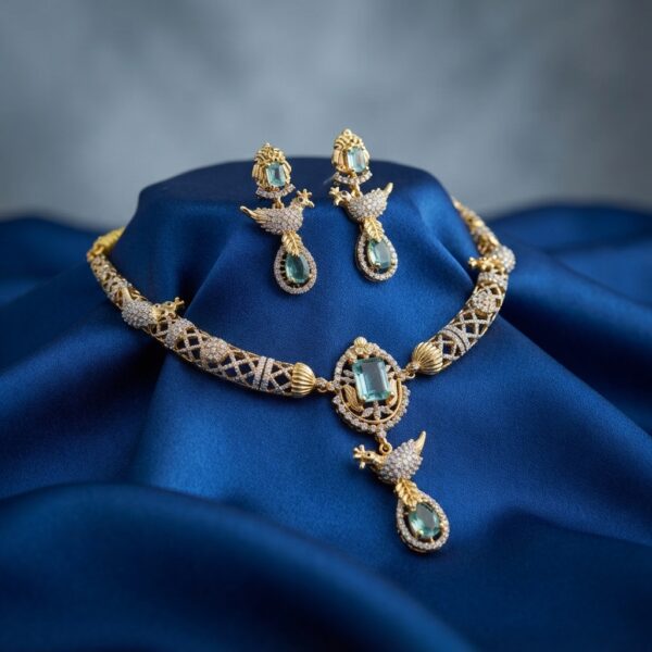 Gold-tone aqua blue necklace set with cubic zirconia, bird motif drop, aqua-coloured stones and matching drop earrings on royal blue fabric