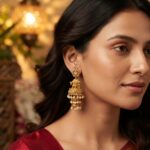 Antique gold-tone temple jhumka earrings with Lakshmi stud tops, cow motif, three-tier bells and faux pearl drops