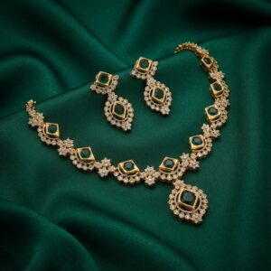 Gold-tone green stone necklace set with square-cut green stones, cubic zirconia halos, centre pendant and matching drop earrings on green fabric