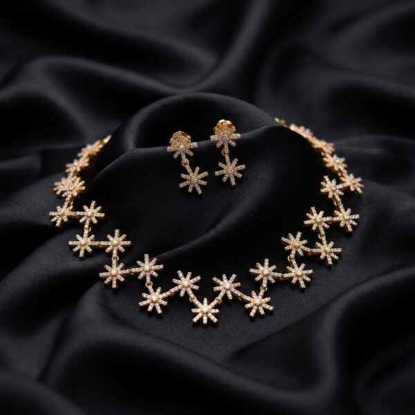 Gold-tone star necklace set with linked cubic zirconia starburst motifs and matching drop earrings on black fabric