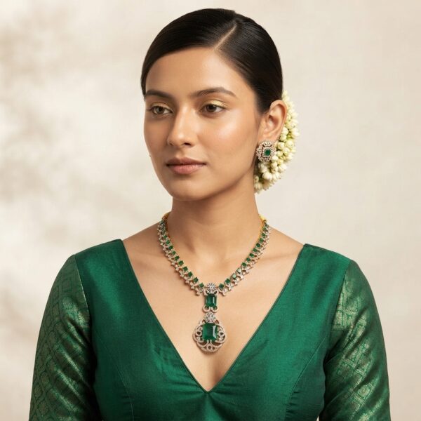 Gold-tone American diamond necklace set with emerald-coloured stones, cubic zirconia detailing and matching stud earrings on navy blue fabric