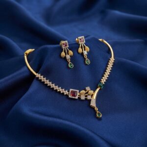 Gold-tone hasli necklace set with rigid collar, cubic zirconia, ruby-coloured and green stones and matching drop earrings on royal blue fabric