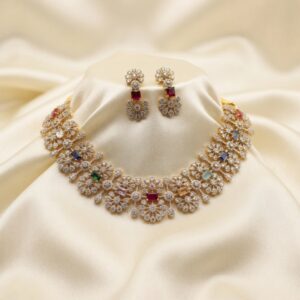 Gold-tone bridal cubic zirconia necklace set with floral clusters, coloured accent stones and matching drop earrings on cream fabric