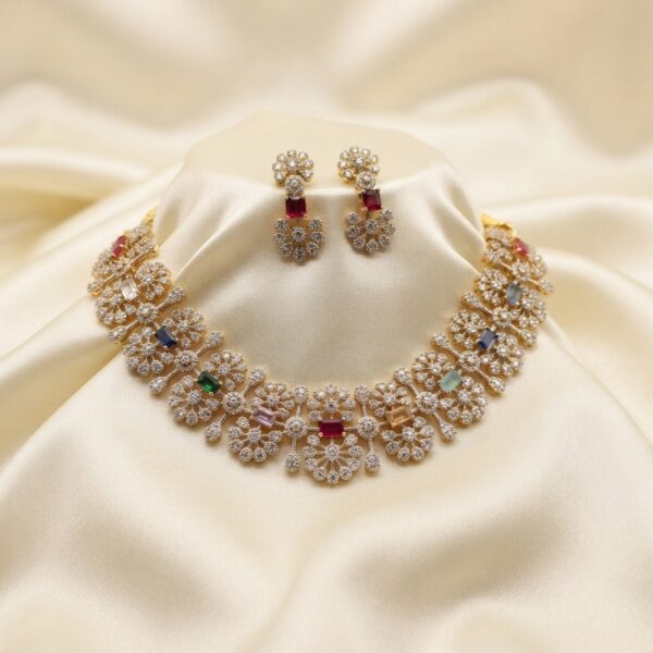 Gold-tone bridal cubic zirconia necklace set with floral clusters, coloured accent stones and matching drop earrings on cream fabric