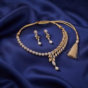 Gold-tone tassel necklace set with cubic zirconia branch design, faux pearl drop, adjustable thread tie and matching drop earrings on navy fabric