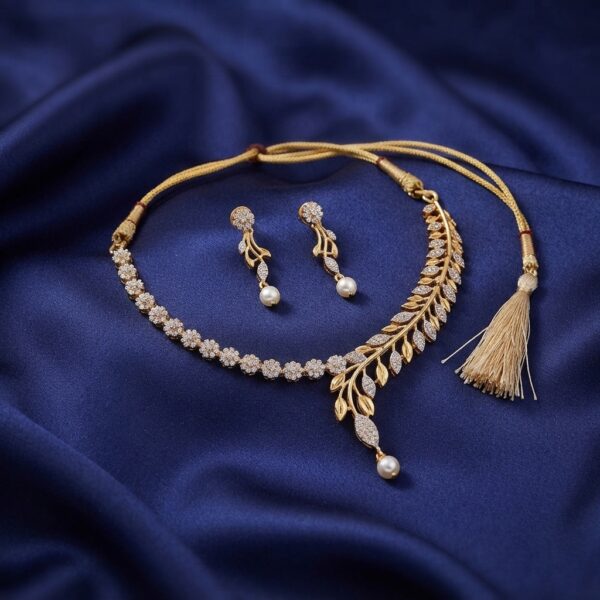 Gold-tone tassel necklace set with cubic zirconia branch design, faux pearl drop, adjustable thread tie and matching drop earrings on navy fabric