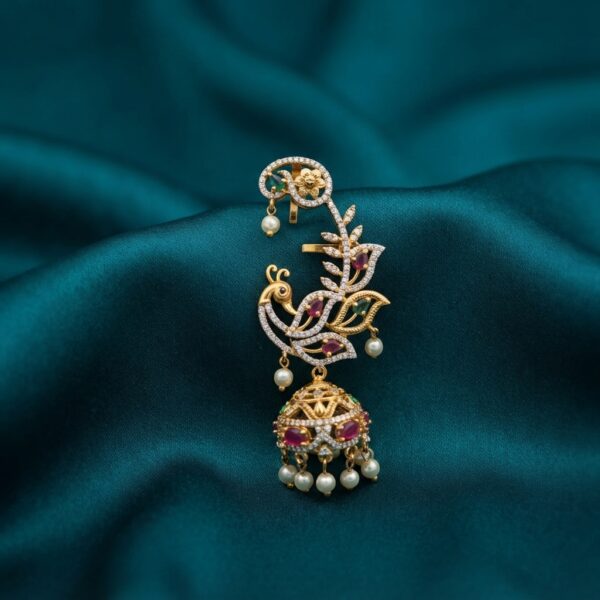 Gold-tone peacock ear cuff earring with cubic zirconia vine, ruby-coloured and green stones, jhumka drop and faux pearl accents on teal fabric