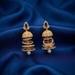gold-tone American diamond-style jhumka earrings with tiered rings and pearl-style drop