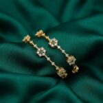 Pair of gold-tone American diamond bangles with floral clusters and green stone-style centres