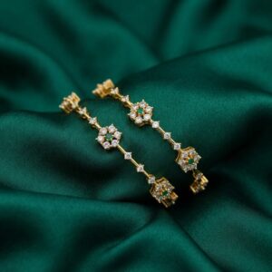 Pair of gold-tone American diamond bangles with floral clusters and green stone-style centres