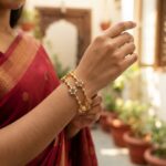 Pair of gold-tone American diamond bangles with floral clusters and green stone-style centres