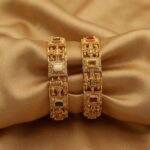 Pair of wide antique gold-tone temple jewellery bangles with figure panels and stone-style