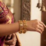 Pair of wide antique gold-tone temple jewellery bangles with figure panels and stone-style