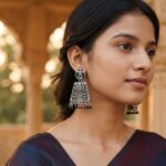 oxidised silver-tone jhumka earrings with Lakshmi motif top and green bead drops