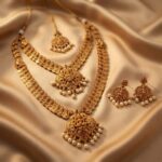 Antique gold-tone double layer necklace set with two necklaces, ornate pendants, faux pearl drops and matching drop earrings on champagne fabric