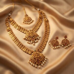 Antique gold-tone double layer necklace set with two necklaces, ornate pendants, faux pearl drops and matching drop earrings on champagne fabric